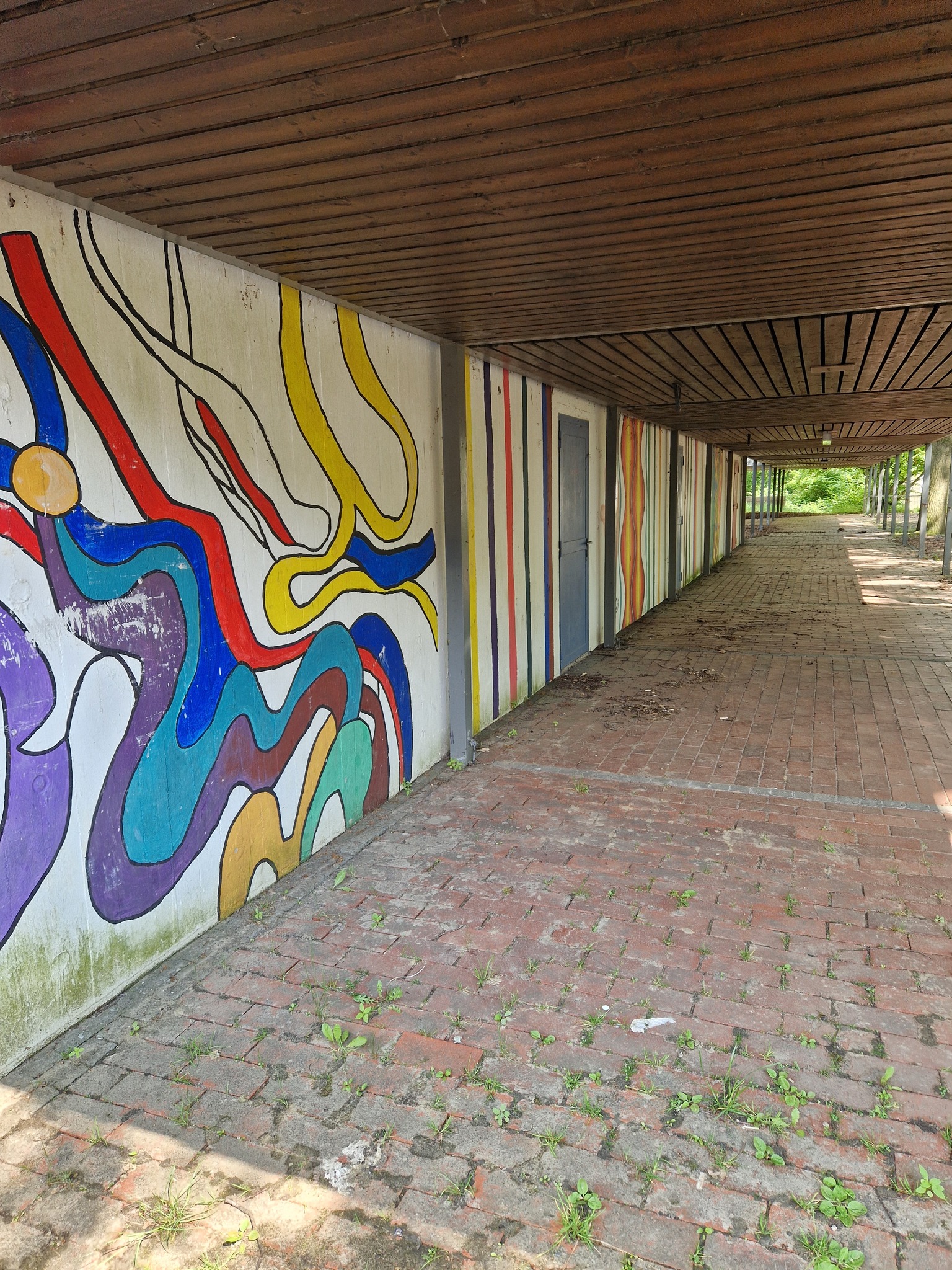 Bunter Schülerkorridor mit verblasster Wandbemalung, heute leer und ungenutzt.